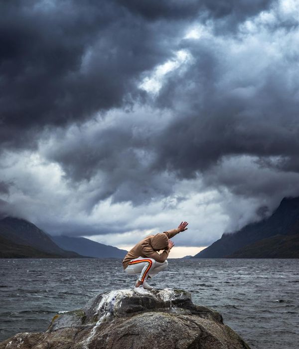 Person in an energetic yoga pose against a dark, dramatic background.